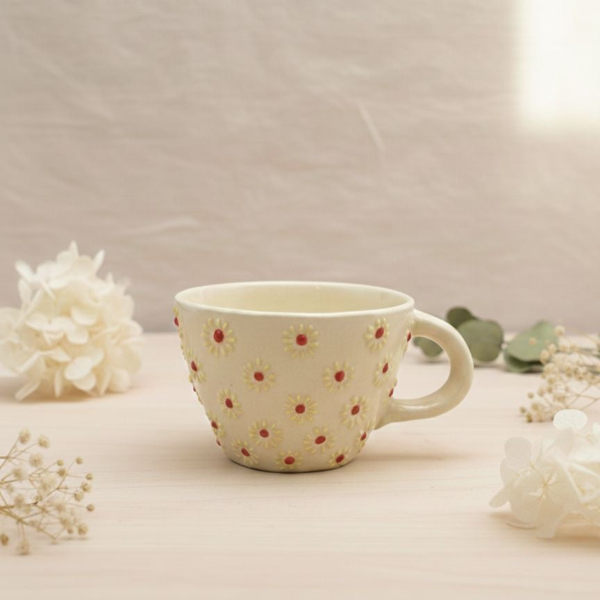 Ceramic mug with floral pattern on a light surface with flowers around