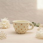 Ceramic mug with floral pattern on a light surface with flowers around